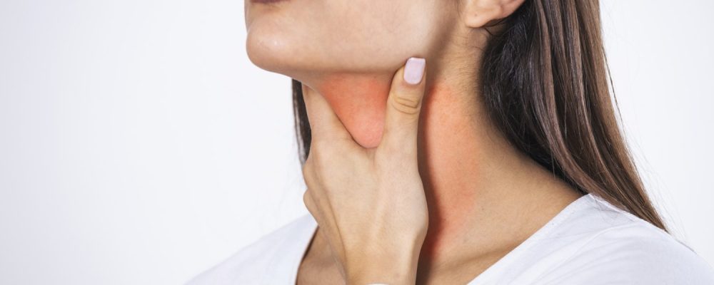 Young beautiful woman suffering from pain in throat, touching inflamed zone on her neck, cropped, empty space, sore throat