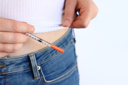 Insulin syringe. A woman with a syringe is about to inject herself with insulin. Diabetes treatment. Medicine and health concept. Inject yourself with insulin at home. Healthcare