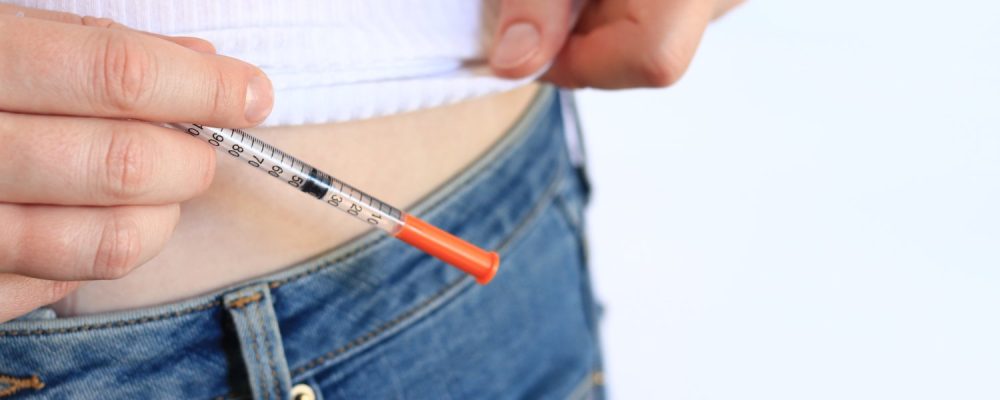 Insulin syringe. A woman with a syringe is about to inject herself with insulin. Diabetes treatment. Medicine and health concept. Inject yourself with insulin at home. Healthcare